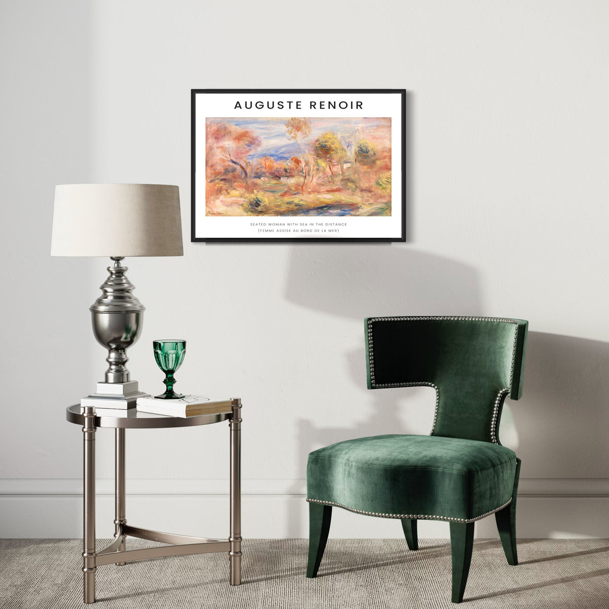 Modern living room with a green velvet accent chair, metallic side table with lamp and glass, and framed Auguste Renoir art poster on a white wall.