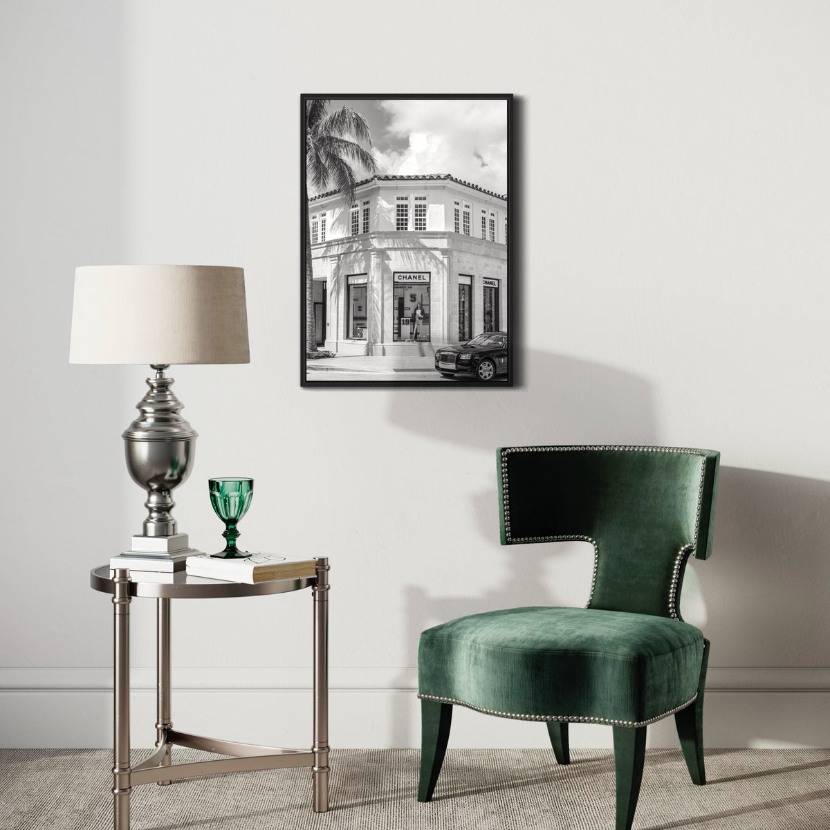 Black and white poster of a luxury boutique on wall above elegant green chair and lamp table
