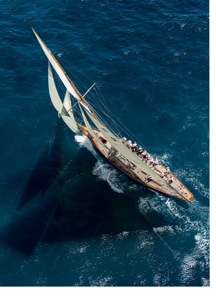 Aerial sailboat poster with a classic wooden sailboat and white sails on blue water