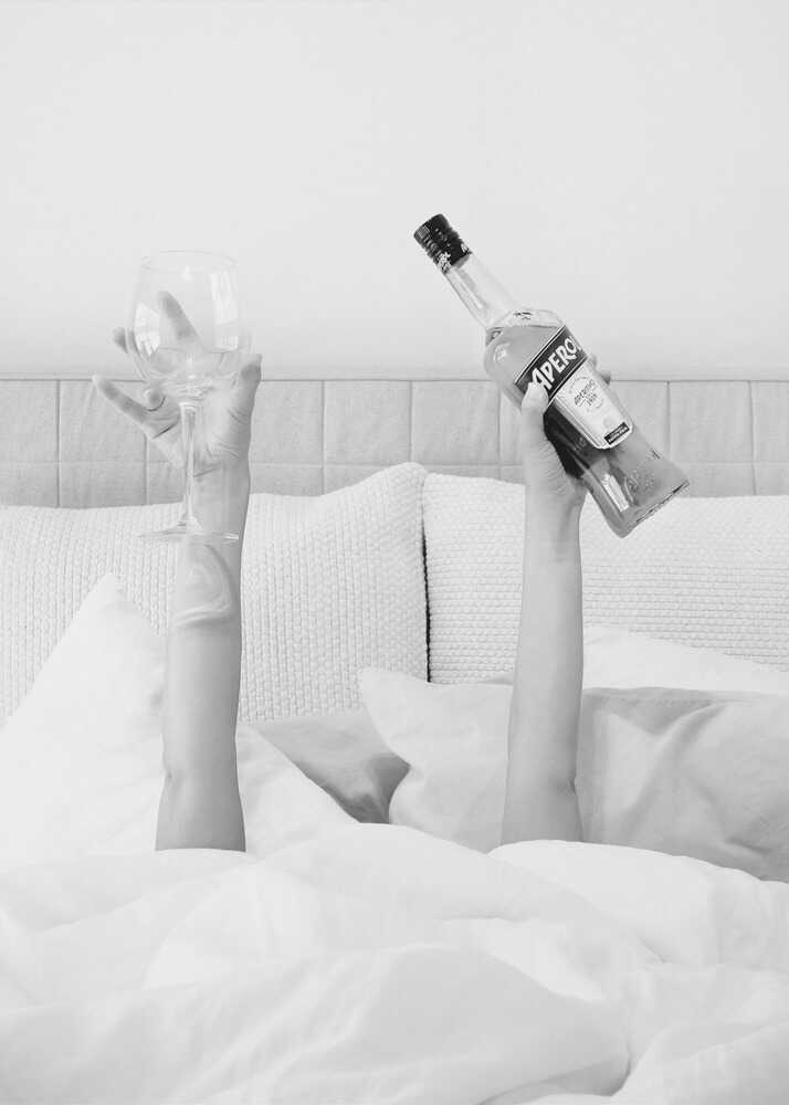 Bed aperol poster with a black and white view of arms holding a wine glass and Aperol bottle from under the covers