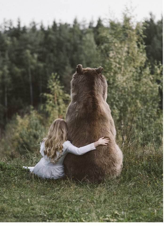 Girl and bear poster with a girl hugging a large bear in a grassy field