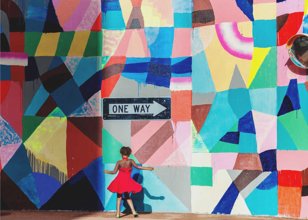 Girl mural wall poster with a girl in a red dress in front of a colorful geometric mural