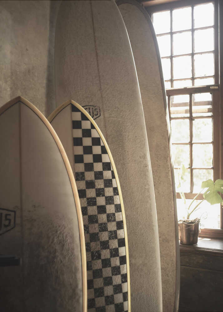 Indoor surfboards poster with several surfboards leaning against a wall near a window