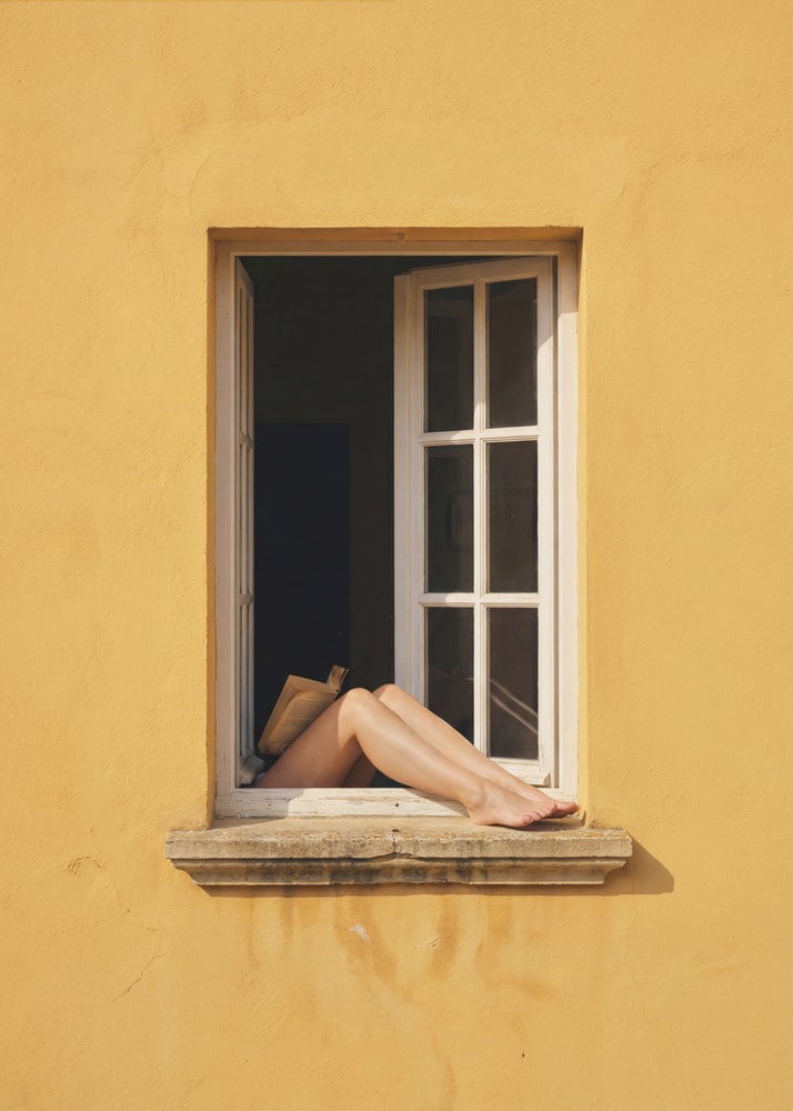 Legs in window poster with legs and a book sticking out of a yellow wall window