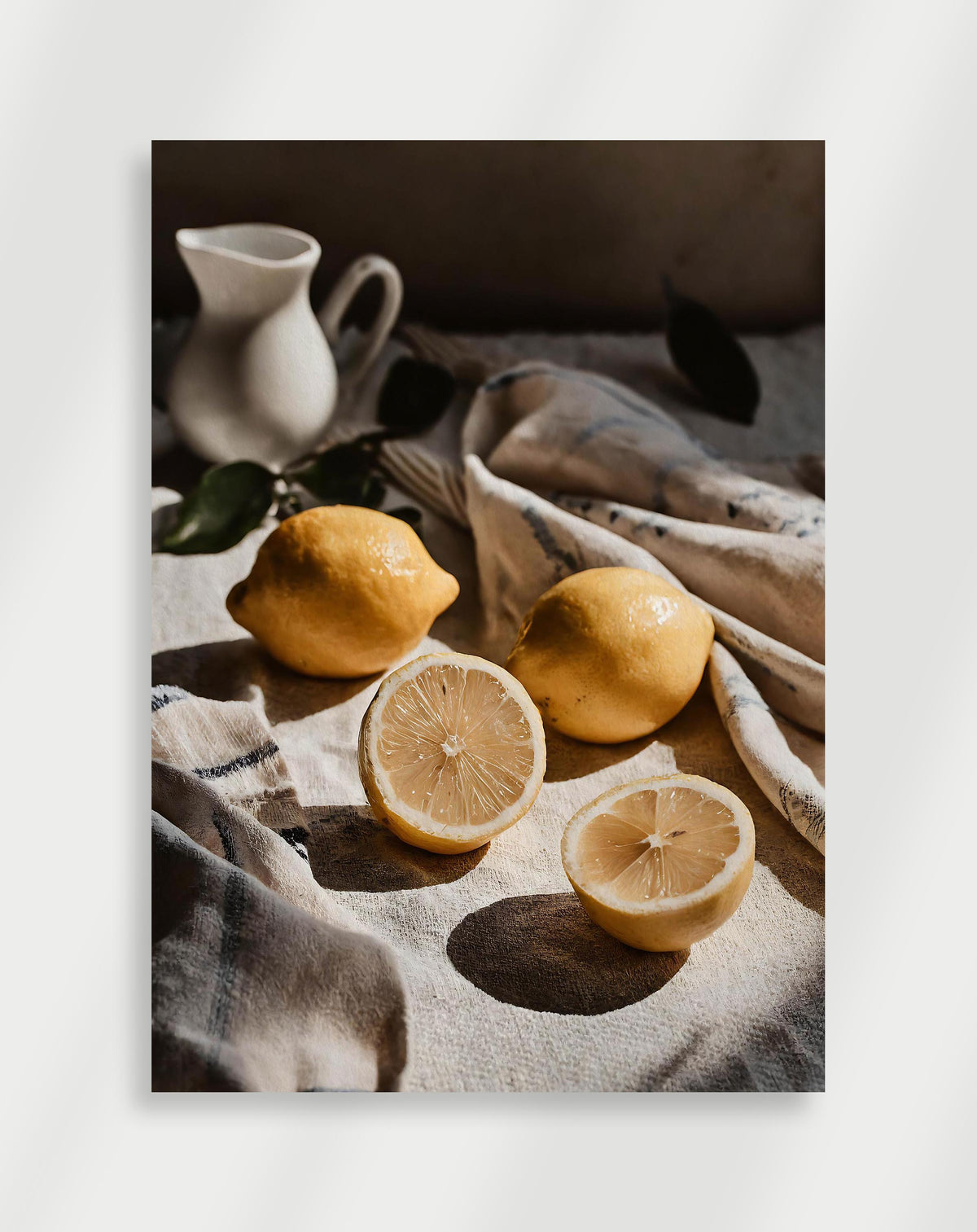 Lemons still life poster with whole and halved lemons on linen cloth with a white pitcher