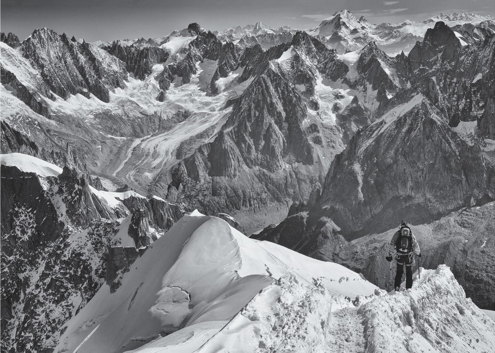 Mountain climber poster with a black and white view of a climber on a snowy peak and mountain range