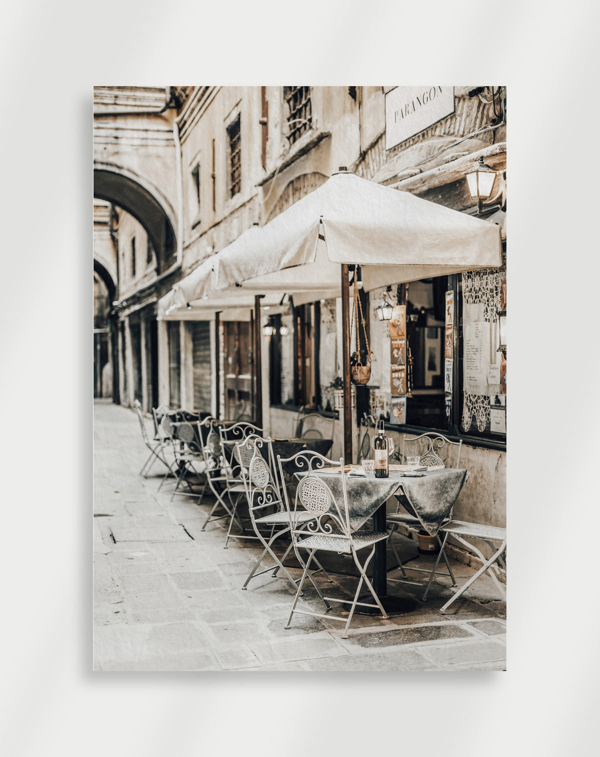 Outdoor cafe street poster with white metal chairs and tables under awnings on a narrow European street