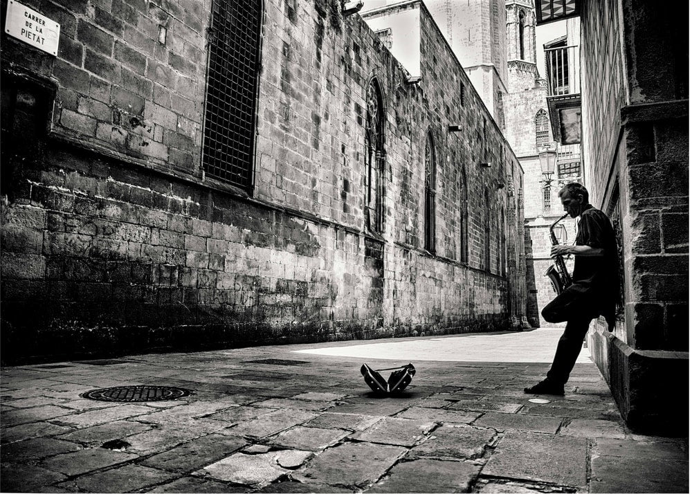 Saxophone alley poster with a black and white view of a man playing saxophone in a stone alley