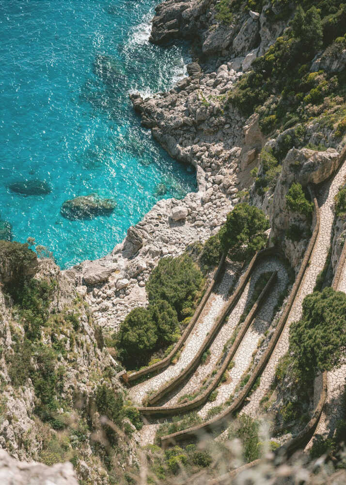 Stone steps cliffs poster with a winding stone path down a rocky cliff to turquoise water